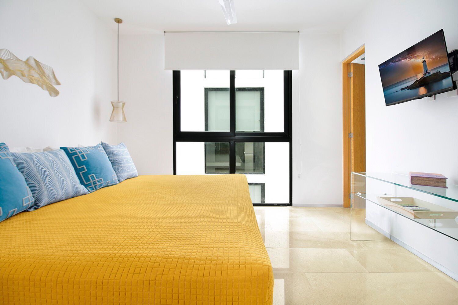 Een moderne slaapkamer met een groot bed, een televisie aan de muur en een glazen kast.