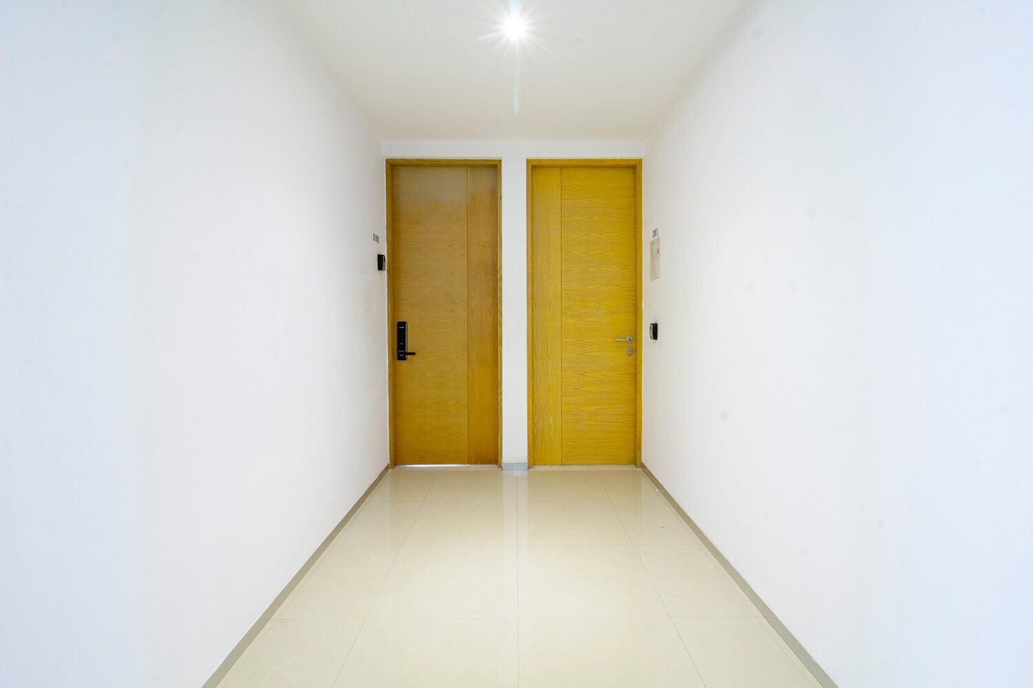 Un couloir avec deux portes, dont une est fermée et l’autre ouverte, menant à une pièce.
