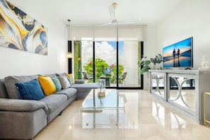 Relax in this stylish living room with a sofa, coffee table, and flat-screen TV, plus a balcony with a view of the sky.