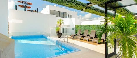 Una piscina exterior moderna amb gandules i una zona de seients amb finestres.