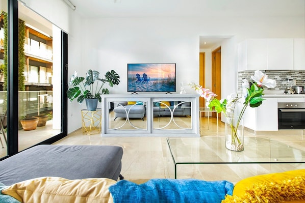 Relax in this stylish living space with a large window offering a view of the outdoors, a flat-screen TV, and a comfortable sofa and armchair.
