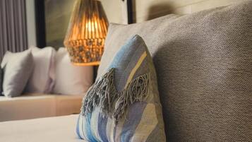 A bed with a grey and blue striped pillow and a grey textured pillow.