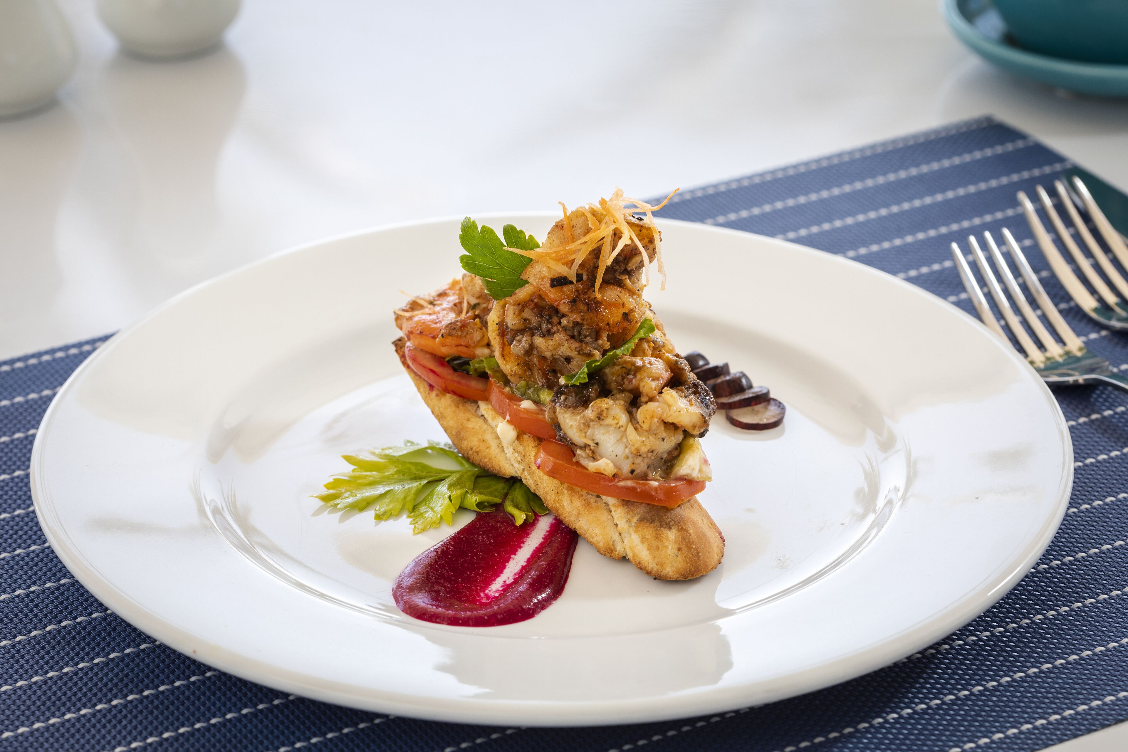 A white plate with a seafood dish, a fork, and a blue placemat.