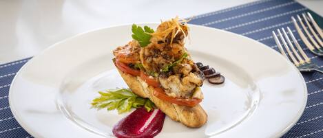 A white plate with a seafood dish, a fork, and a blue placemat.