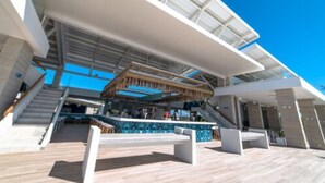 Un espacio exterior moderno con barra, asientos y una escalera que sube a un nivel superior.