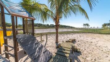 Relax in a shaded beachside haven with ocean views and a palm tree silhouette.
