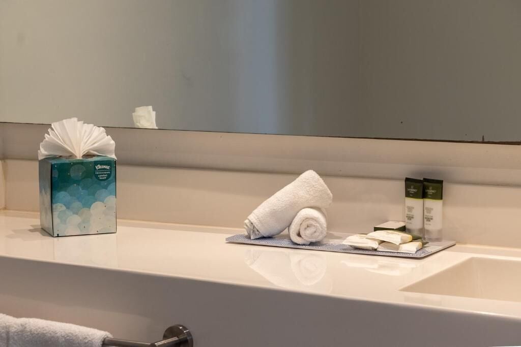 Un baño con toalla, artículos de aseo y caja de pañuelos.
