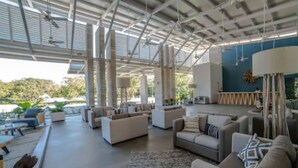 Amplia sala de estar moderna con techos altos y ventanas grandes, que cuenta con muebles contemporáneos y vistas al exterior.