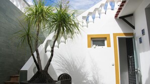 Un bâtiment blanc avec une porte et une fenêtre, un pot de fleurs et un escalier.