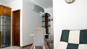 Un espace de vie compact comprenant un coin cuisine, un coin repas avec une table et des chaises, et un canapé.