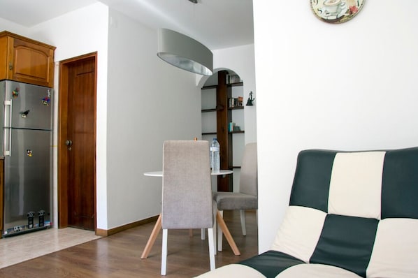 A compact living space with a kitchenette, a dining area with a table and chairs, and a sofa.