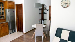 Un espace de vie compact comprenant un coin cuisine, un coin repas et un coin salon.