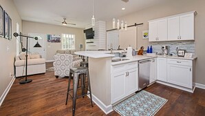 Una cocina moderna con armarios blancos, una isla central y un área de comedor con mobiliario estampado.