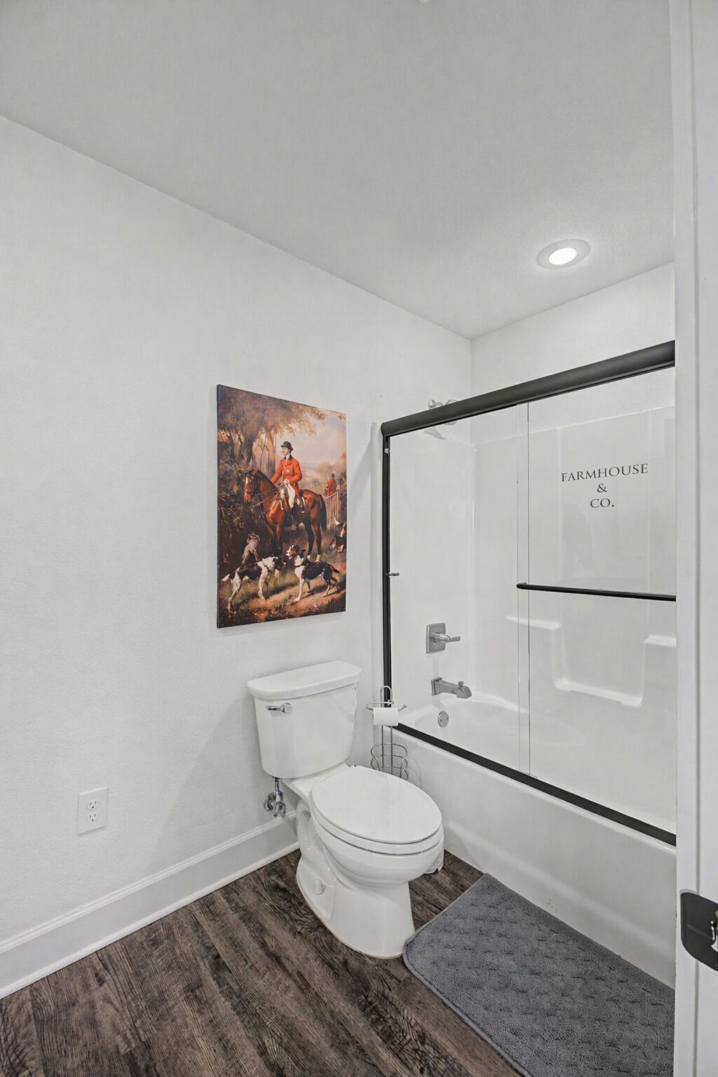 Ein Badezimmer mit Toilette, einer Dusche mit Glastür und einem Bild an der Wand.