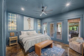 A bedroom with a bed, bench, and a ceiling fan.