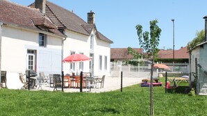 Ein weißes Haus mit Ziegeldach, umzäunter Garten und Gartenmöbeln.