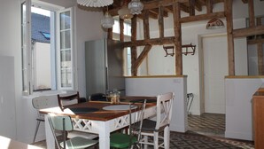 Ein Essbereich mit Holztisch und Stühlen, einem Kühlschrank und Pendelleuchten.