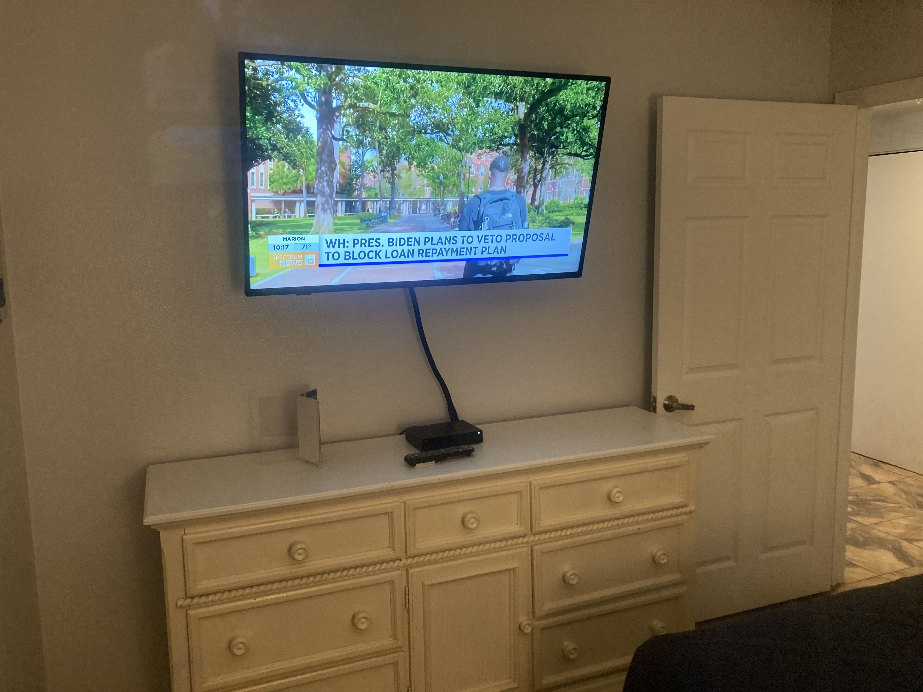 Ein Fernseher an der Wand über einer weißen Kommode mit Schubladen.
