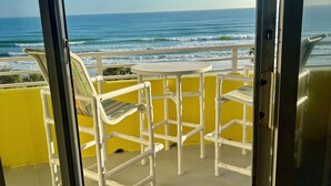 A balcony with a view of the ocean, a white chair, and a yellow wall. - Ocean Walk Resort (Daytona Beach)