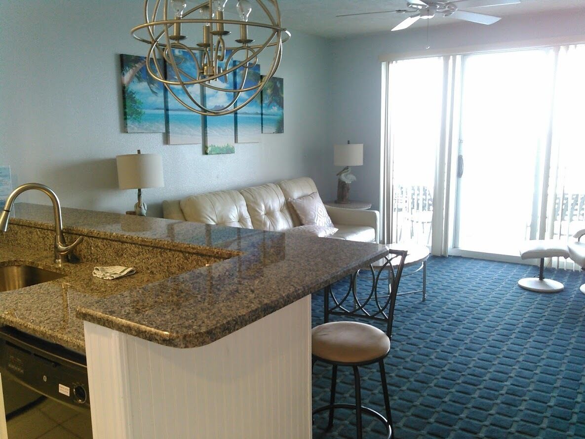 A modern kitchen with granite countertops, a built-in dishwasher, and a bar area with stools.