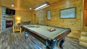 A pool table in a wooden room with a fireplace, a television, and a map on the wall. - Logging Memories | Mtn Views + Hot Tub + Games (Blue Ridge)