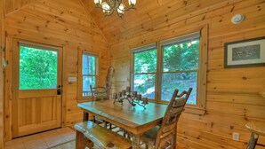 A wooden cabin interior with a dining table, benches, and a chandelier. - Logging Memories | Mtn Views + Hot Tub + Games (Blue Ridge)