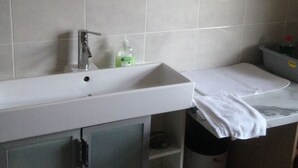 A bathroom with a white sink, a mirror with a pink frame, and a toilet. - The Tackroom is a one bedroom Apartment just a short walk from Fanore Beach (Ballyvaughan)