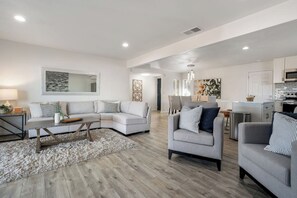 Un salón amplio con un sofá modular, una mesita de centro pequeña y un sillón gris.