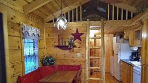 A wooden interior with a dining area, a ladder, and a kitchen with wooden cabinets and appliances. - Elk Cabin - 2 Bedroom/1 Bath Vacation Rental (Franklin)