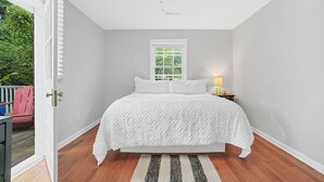 A bedroom with a bed, a window, a ceiling fan, and a door leading to an outdoor area. - HEART OF DOWNTOWN (Riverwalk, River View, Walk to Shopping, Dining, and Spirits) (Wilmington)