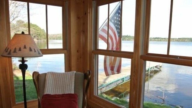 Una baita con ampie finestre, una lampada e una bandiera americana.