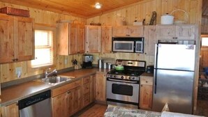 Una cucina in stile baita con lavastoviglie, piano cottura, microonde e frigorifero.