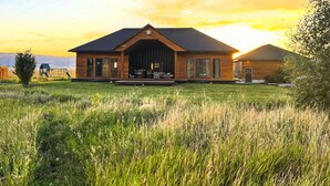 Een modern gebouw met een ruime entree, een overdekt terras en een grasveld op de voorgrond.