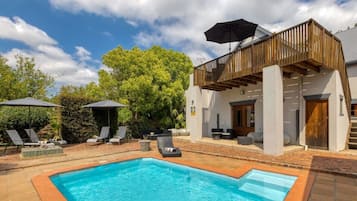 Una piscina al aire libre, sombrillas, sillones reclinables de piscina