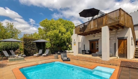 Una piscina al aire libre, sombrillas, sillones reclinables de piscina