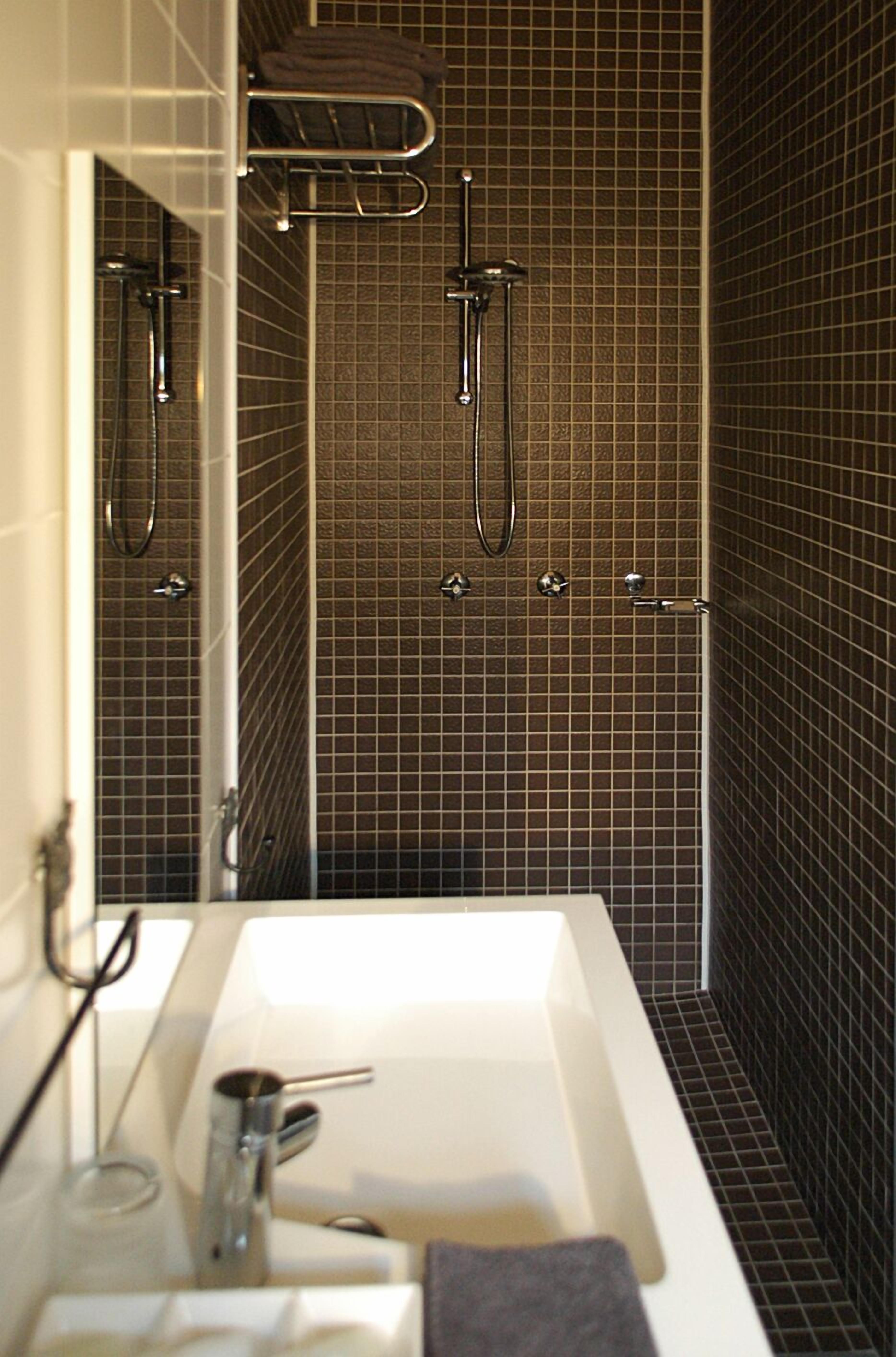 A bathroom with a white sink, a mirror, and a shower area with chrome fixtures.