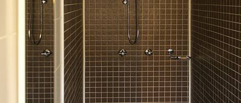 A bathroom with a white sink, a mirror, and a shower area with chrome fixtures.