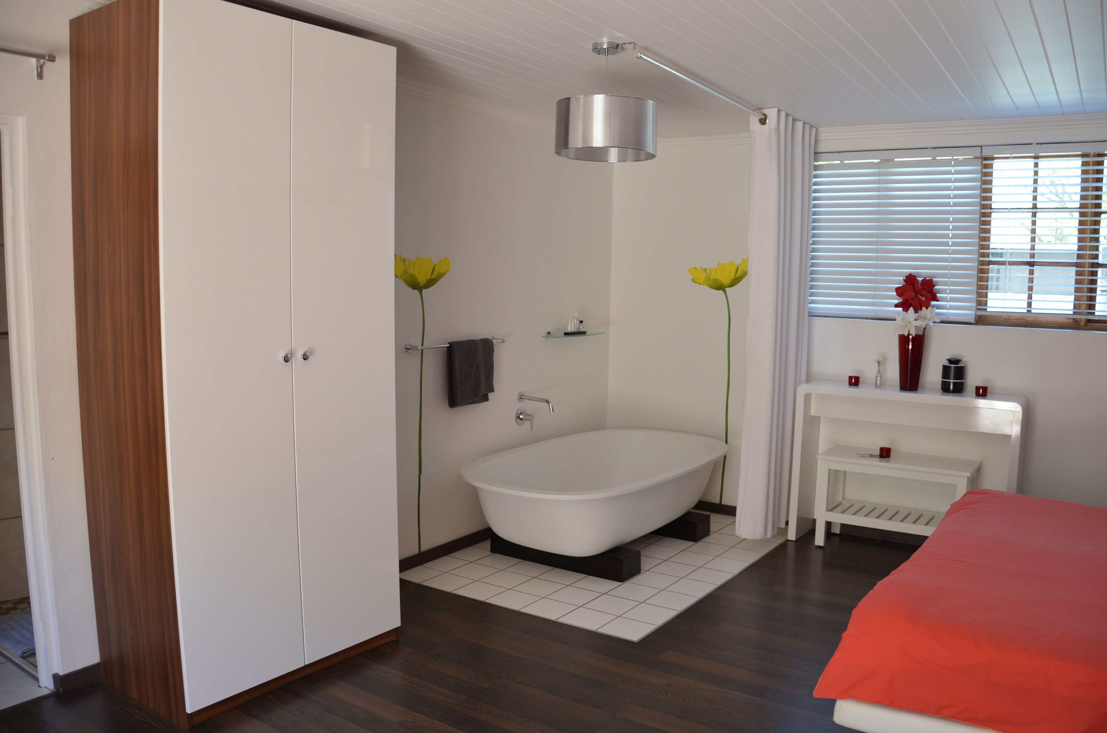 A modern bathroom with a freestanding bathtub, a vanity with a mirror, and a window with blinds.