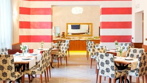 Un espace repas avec des murs à rayures, un bar central et des chaises à motifs.