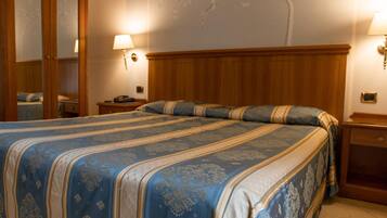 Ein Hotelzimmer mit einem großen Bett, einem Holz-Kopfteil, zwei Nachttischen mit Lampen und einem Spiegel an einer Wand.
