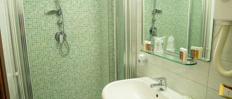 A bathroom with a glass shower enclosure, a white sink, and a mirror above the sink.