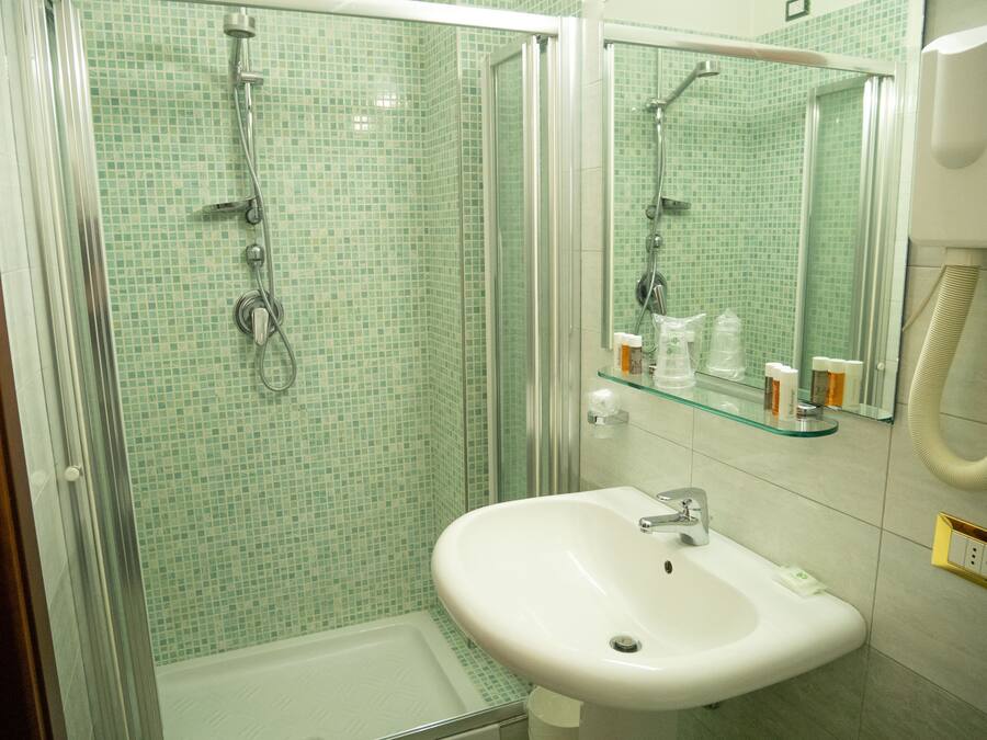 Une salle de bain avec une douche à parois de verre, un lavabo blanc et un miroir au-dessus du lavabo.