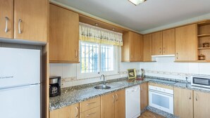 A compact kitchen with wooden cabinets, a built-in oven, a microwave, and a coffee maker.