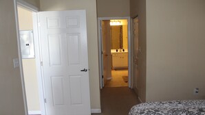 A bedroom with a bed, a door leading to a bathroom, and a hallway.