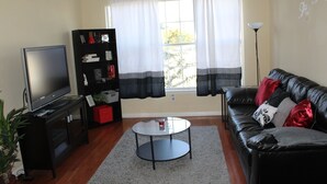 A living room with a TV, bookshelf, leather sofa, and a coffee table.