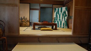 Una habitación japonesa tradicional con suelo de tatami, una mesa de madera baja y un cojín.