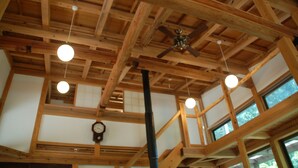 Habitación con vigas de madera a la vista, ventilador de techo y lámparas colgantes.