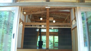 Un interior de madera con techo alto, ventanas amplias y una chimenea a la vista.