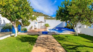 Un patio con piscina, paredes blancas y árboles.