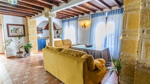 Una sala acogedora con un sofá amarillo, una mesa de comedor y cortinas azules.